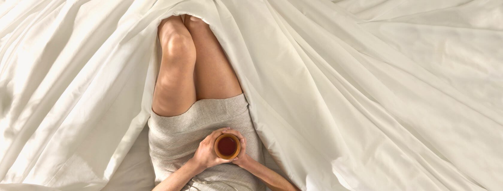 Woman lying comfortably in Saatva sheets.