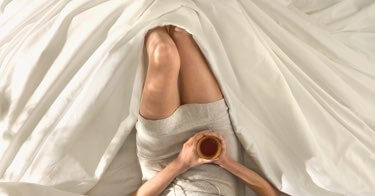 Woman lying comfortably in Saatva sheets.