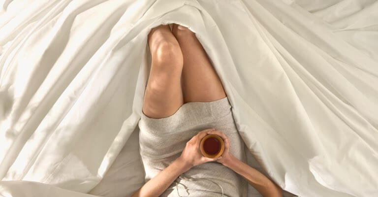Woman lying comfortably in Saatva sheets.