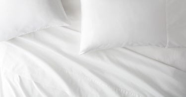 Saatva Signature Sateen sheets and pillows on a bed.