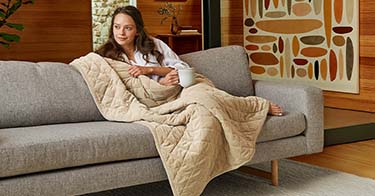 Woman wrapped comfortably in a weighted blanket.